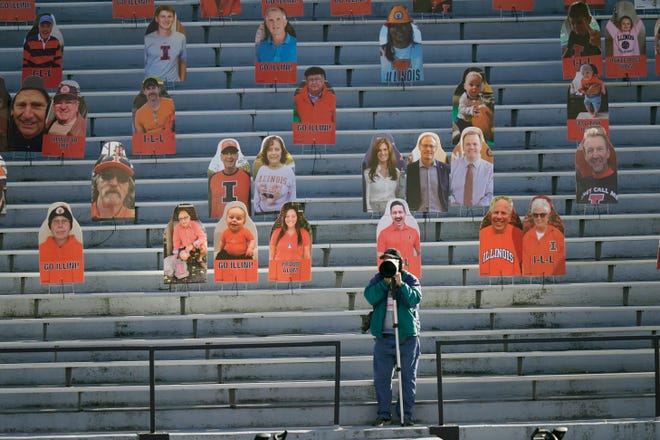 A photographer shoots pregame warmups near cardboard cutouts of fans before an NCAA college football game between Illinois and Purdue Saturday, Oct. 31, 2020, in Champaign, Ill. (AP Photo/Charles Rex Arbogast)