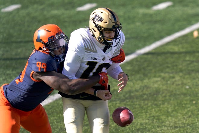 Illinois defensive lineman Owen Carney Jr., left, strips Purdue quarterback Aidan O'Connell of the ball during the first half of an NCAA college football game Saturday, Oct. 31, 2020, in Champaign, Ill. (AP Photo/Charles Rex Arbogast)